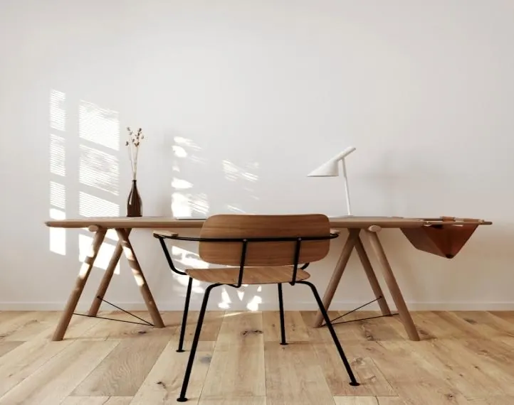 Table de repas en bois sur un parquet clair à lames larges, devant un mur blanc.