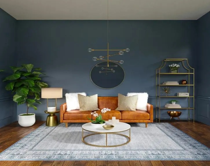 Salon sur mur bleu : canapé en cuir cognac, tapis clair et suspension à globes dorés.