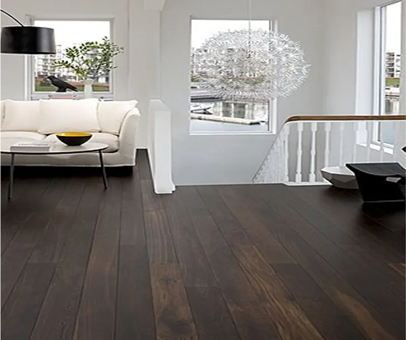 Séjour à l’étage : parquet foncé à lames larges, canapé blanc et départ d’escalier.